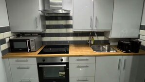 A modern kitchen with grey cabinets, a microwave, a toaster, and a sink. - Place to stay in Erith (Erith)