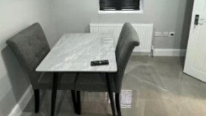 A dining area with a table and chairs, a window with blinds, and a radiator. - Place to stay in Erith (Erith)