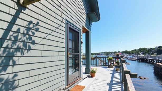 A waterfront property with a wooden deck, a large window, and a view of the marina.