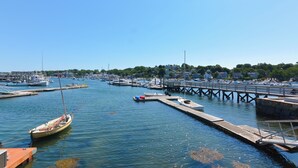 A marina with boats docked, a pier, and a view of the town in the background.