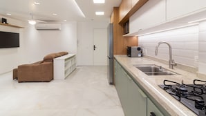 A modern kitchen with a built-in gas stove, stainless steel sink, and wooden cabinets. - Comfort in Leblon 10 Minutes From the Beach Bm802 (Rio de Janeiro)