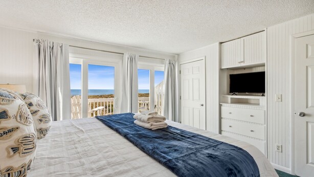 Une chambre avec un lit, une télévision et vue sur la plage.