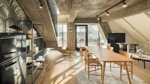 A modern loft with a kitchen, dining area, and a large window overlooking a cityscape. - Phoenix Aparthotel (Galati)