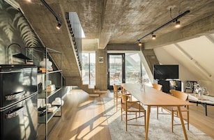 Un loft moderno con cocina, comedor y un ventanal grande con vistas a un paisaje urbano.