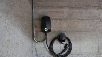 Une borne de recharge EVBOX fixée au mur, avec un câble branché à une prise de courant.