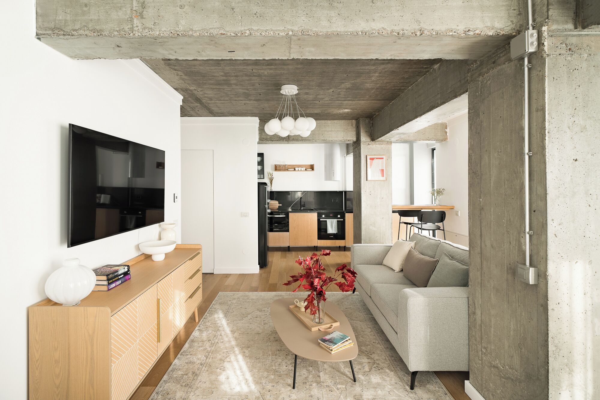 A modern living room with a flat-screen TV, wooden console, and a beige sofa.