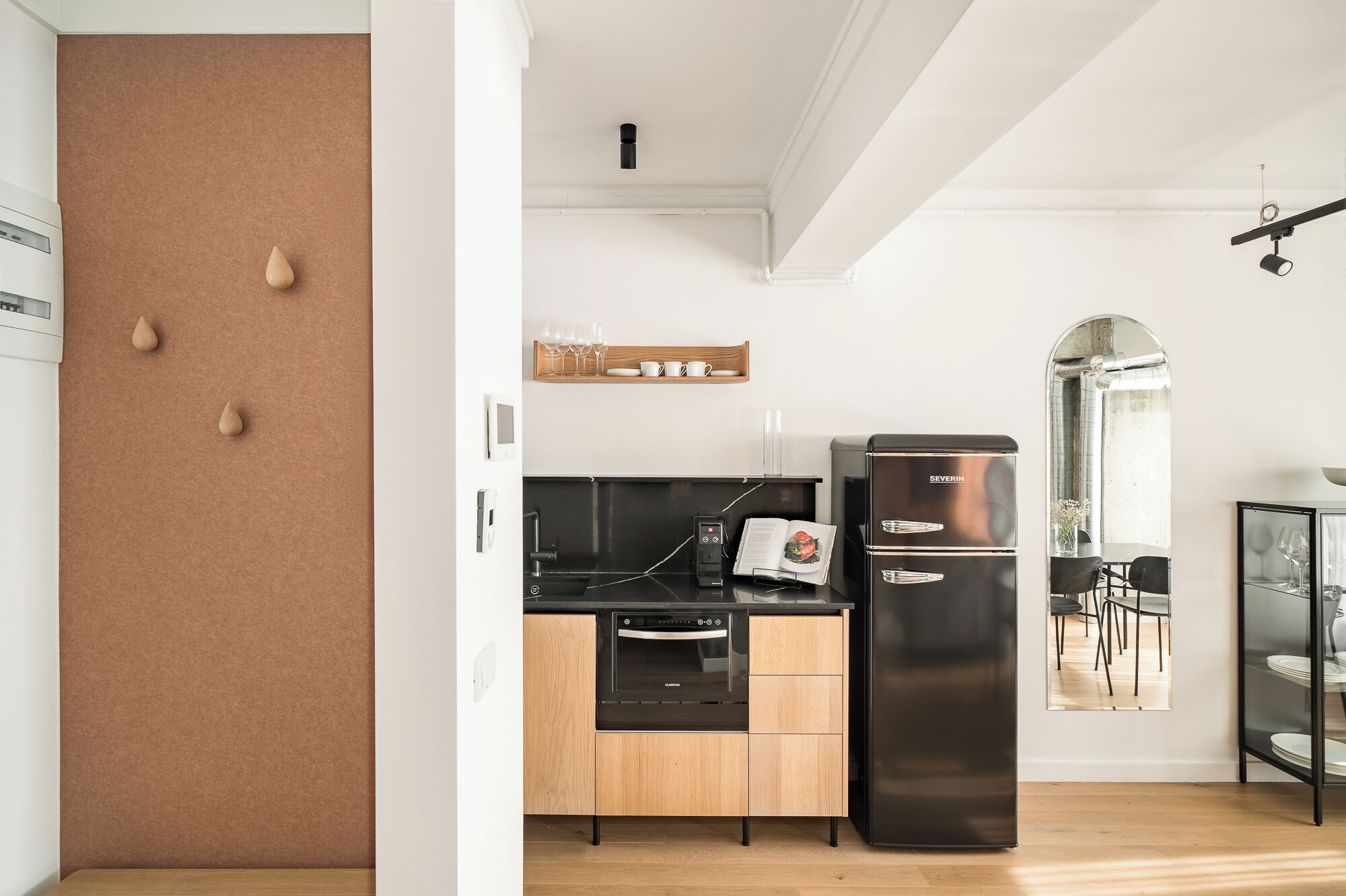 A modern kitchen with a black refrigerator, wooden cabinets, and a built-in oven.
