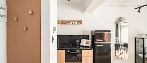 A modern kitchen with a black refrigerator, wooden cabinets, and a built-in oven.