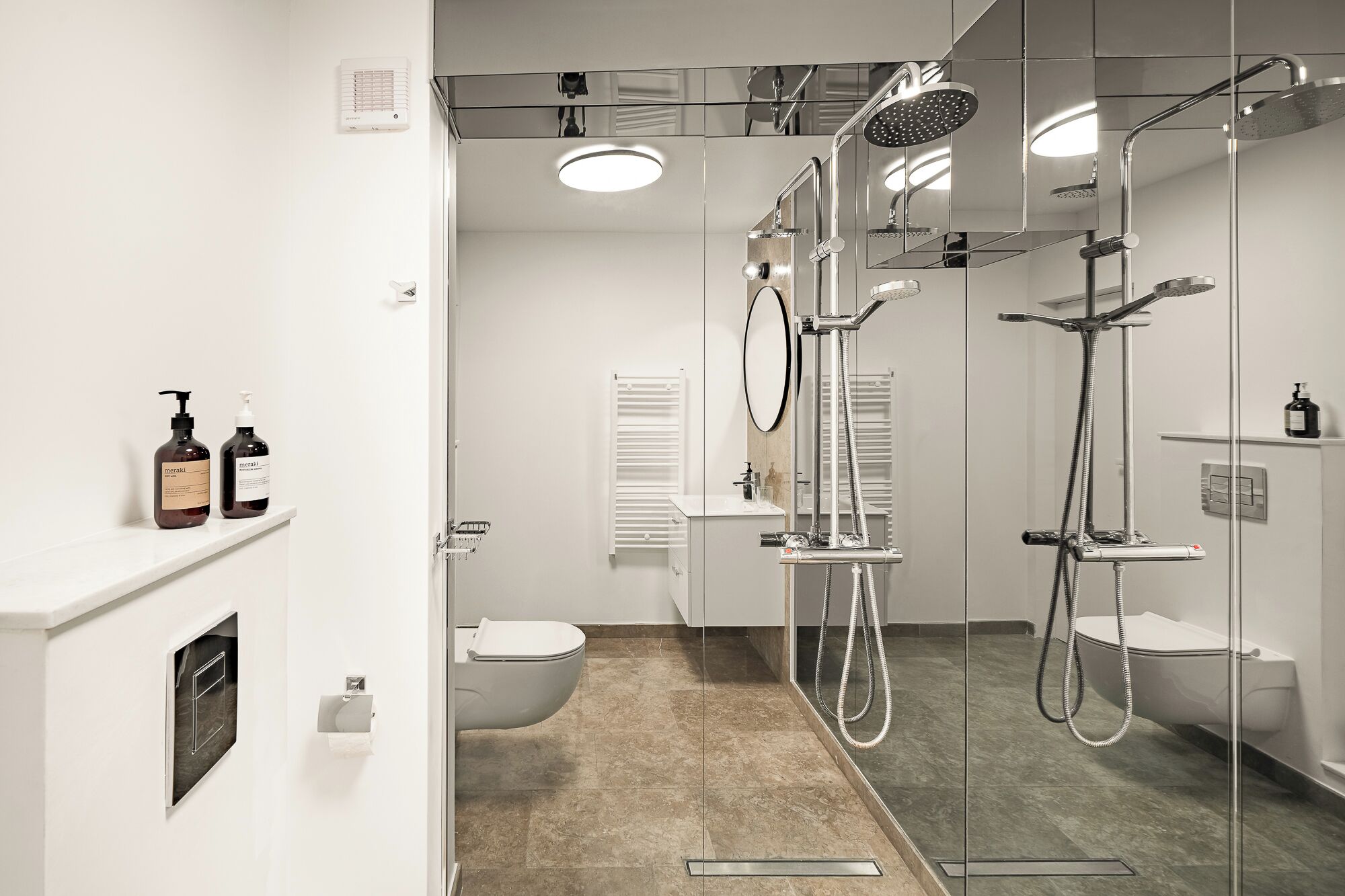 A modern bathroom with a glass-enclosed shower, a toilet, and a sink.