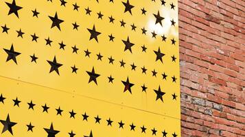 Un panel amarillo con estrellas negras sobre un muro de ladrillo.