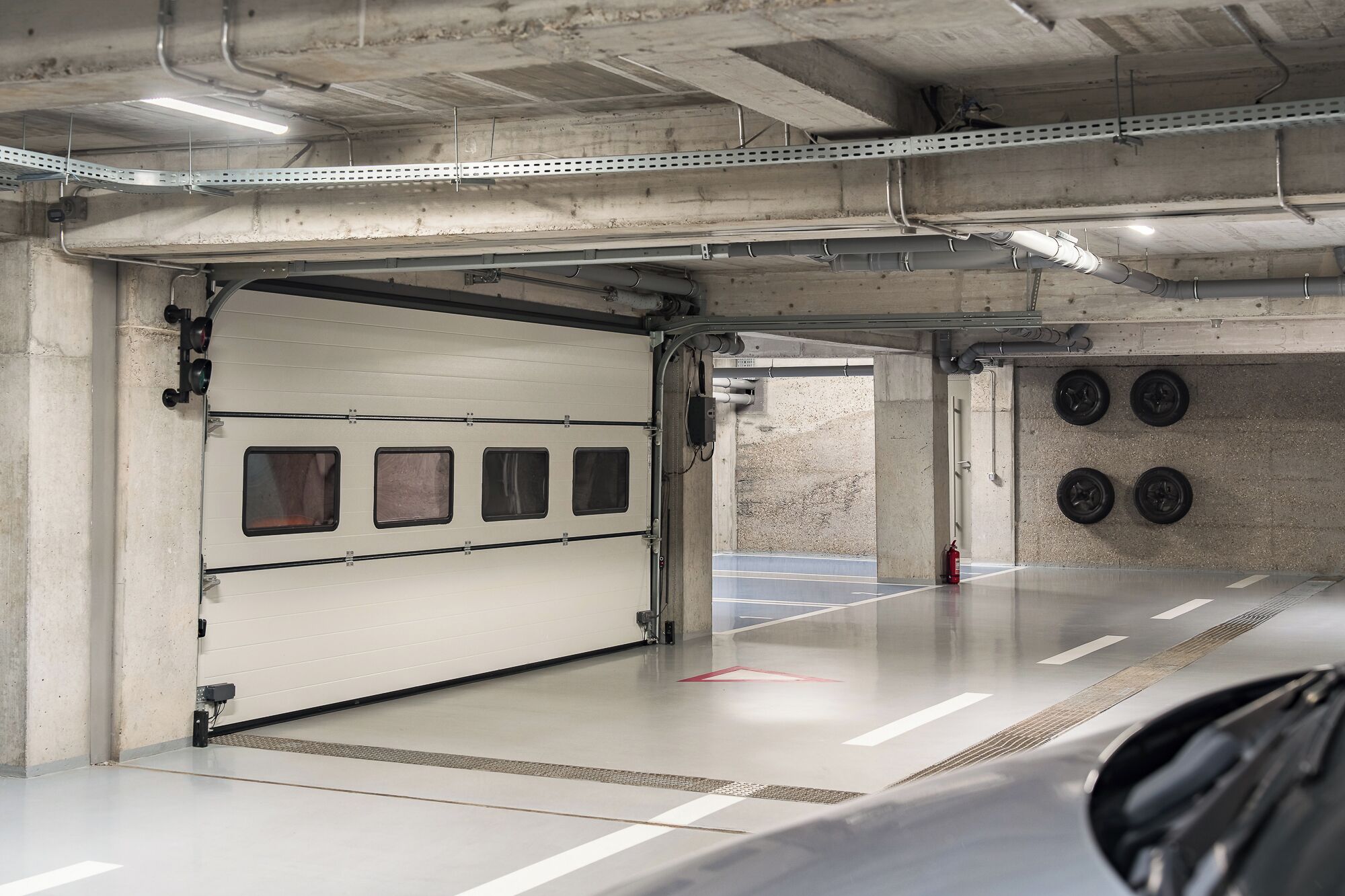 An empty parking garage with concrete walls, metal shelving, and a fire extinguisher.