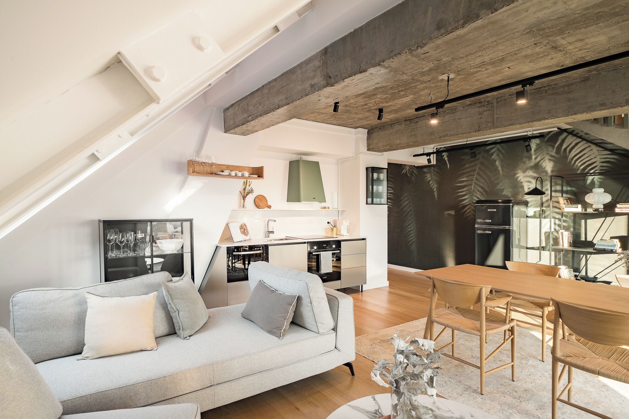 Un apartamento loft moderno con cama de altillo, kitchenette, comedor y sala de estar con sofá y sillones.