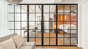 A modern interior with a sliding glass door leading to a bedroom with a metal bed frame and a wooden floor. - Phoenix Aparthotel (Galati)