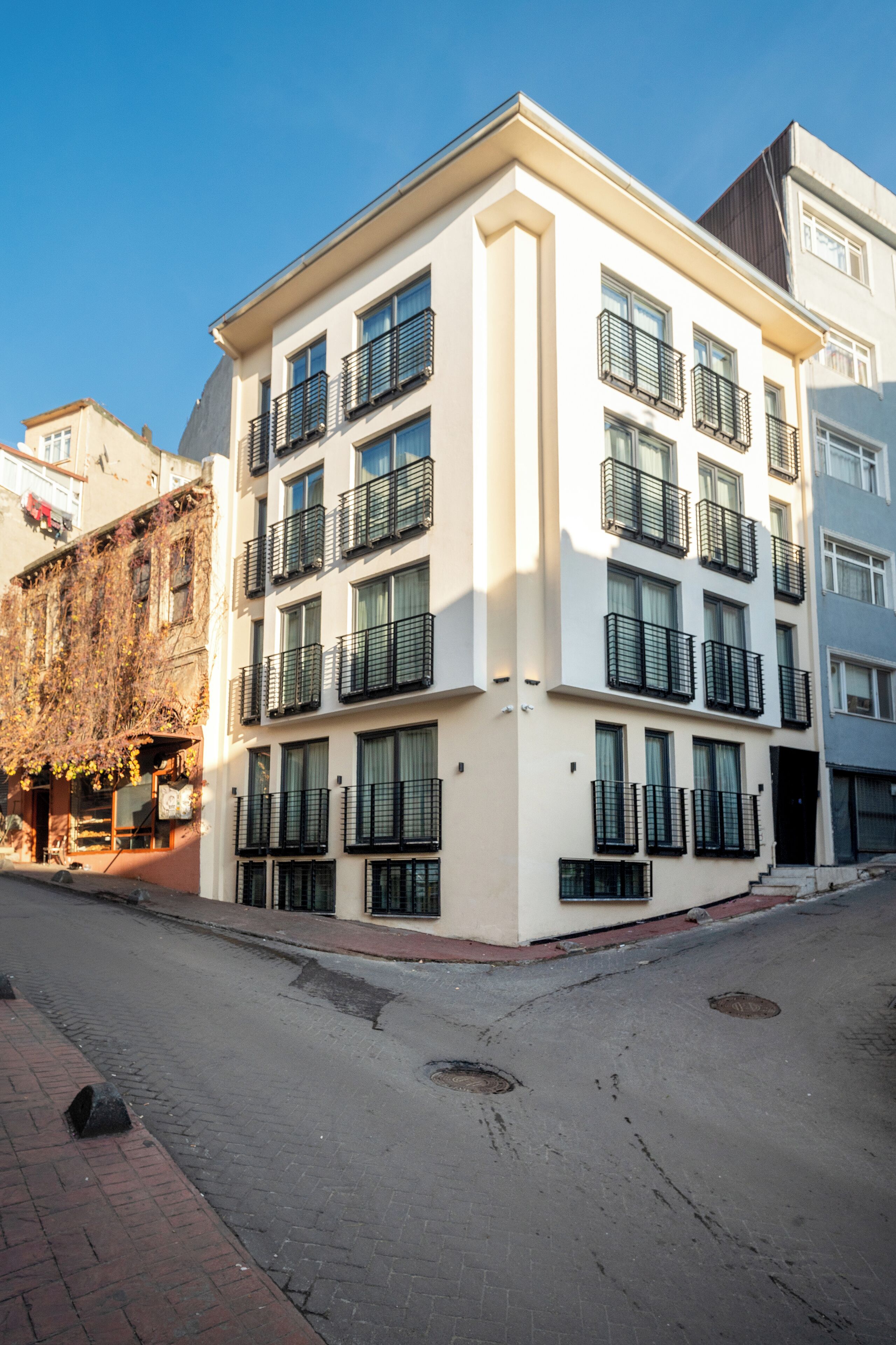 A multi-story building with balconies, a brick-paved street, and a clear sky.