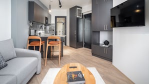 A modern kitchen with grey cabinets, a built-in microwave, and a large flat-screen TV. - Urban Quarters - Firuzaga (Istanbul)