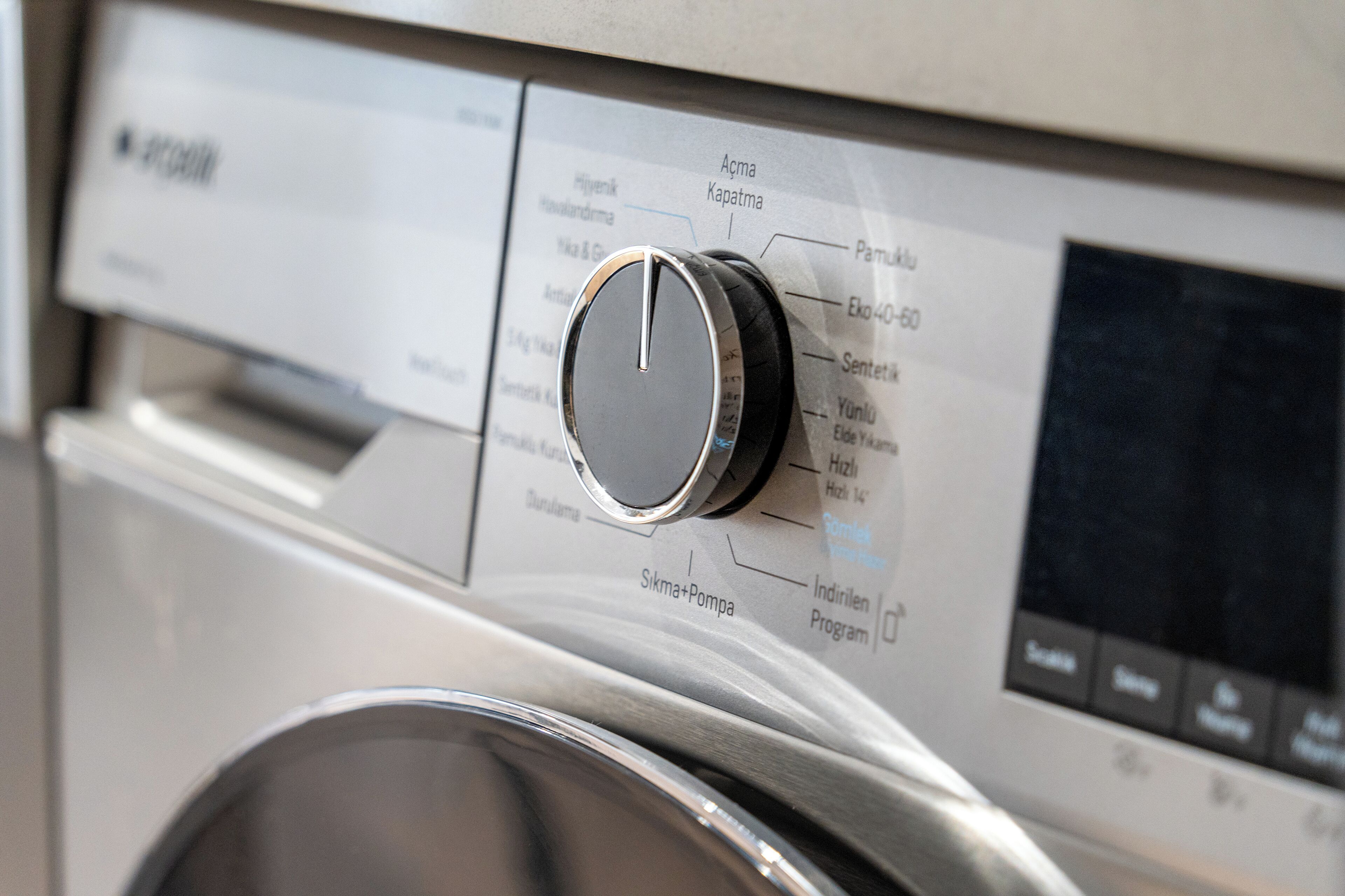 A washing machine with a control panel featuring various settings and a digital display.