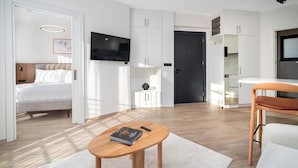 A modern, well-lit room with a bed, a wooden table, a TV, and a kitchen area. - Urban Quarters - Firuzaga (Istanbul)