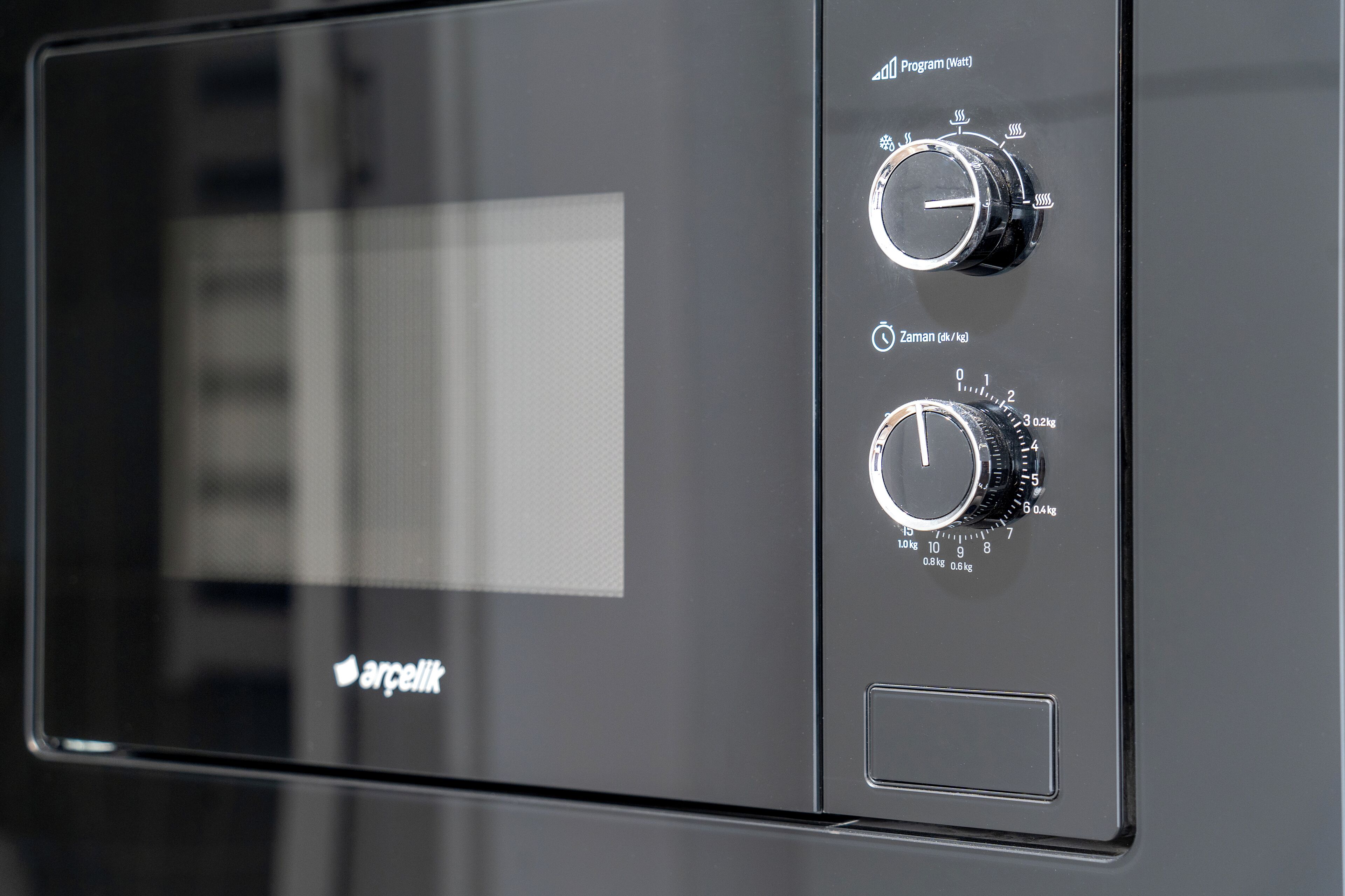 A control panel with two dials labeled "Program (Wet)" and "Zaman (kg)" on a black appliance.