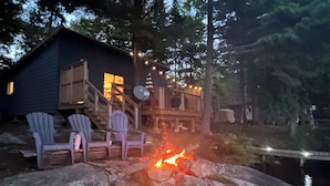 A cabin with a deck, outdoor seating, and a fire pit. - Lakeside Serenity: Cozy Retreat on Ahmic Lake (Magnetawan)