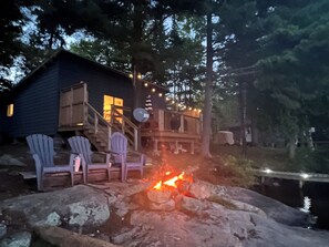 Une cabane dotée d’une terrasse, d’un espace salon extérieur et d’un foyer.