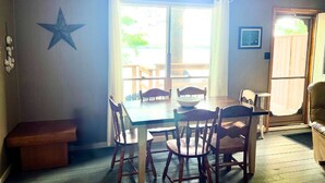 Un coin repas avec une table et des chaises, une décoration en forme d’étoile au mur et une vue dégagée par une grande fenêtre.