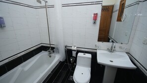 Bathroom features a bathtub, toilet, and sink, with a shower curtain rod and hand dryer.