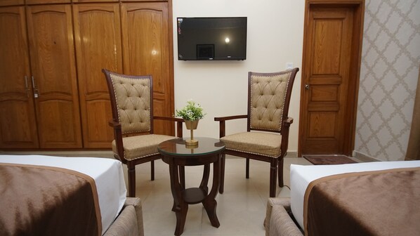 Relax in a classic hotel room with two single beds, a flat-screen TV, and a cozy atmosphere.