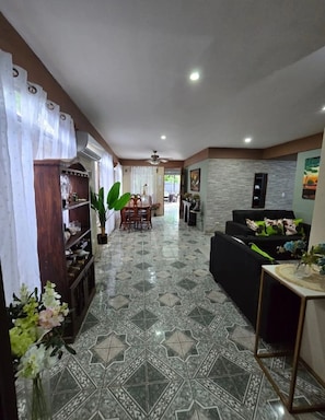 A spacious living area with a dining table, black sofa, and decorative plants. - Casa Nova Quepos, only 9 km from Manuel Antonio beach Costa Rica.  (Quepos)