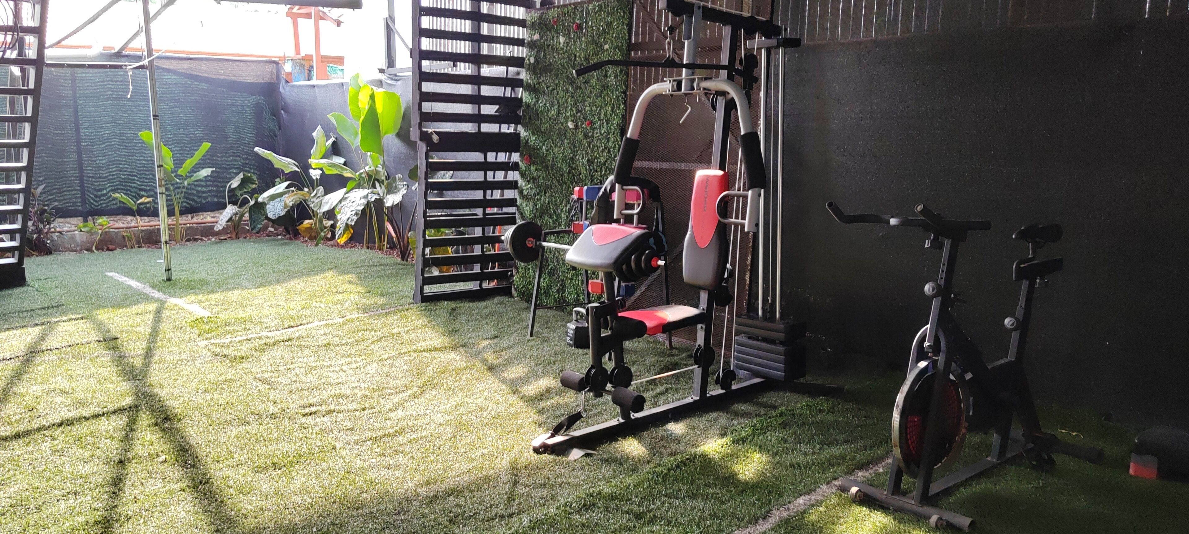 A gym with exercise equipment, a stationary bike, and a green artificial turf floor.