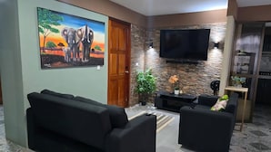 Un salon avec un canapé, un téléviseur, un mur en pierre et un tableau.