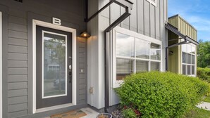 A modern house with a grey exterior, a front door labeled 'B', a small porch with steps, and a potted plant.