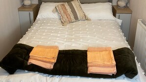 Un lit bien fait, avec une couette blanche, deux oreillers et deux serviettes pliées.