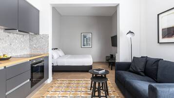 Un espacio habitable compacto con kitchenette, cama, sofá y una pequeña mesa.