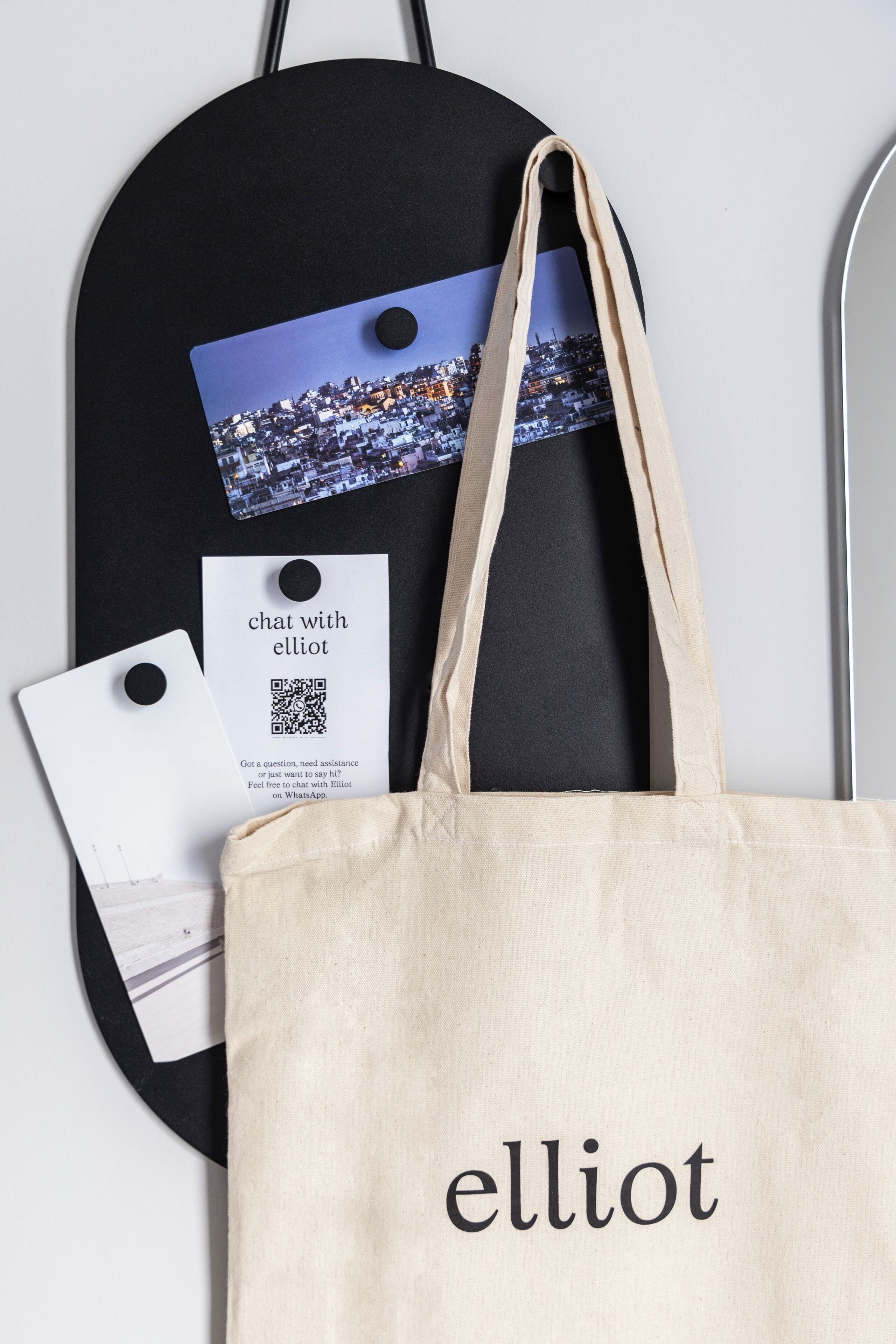 A black tote bag with a QR code and a tag hanging on a wall.