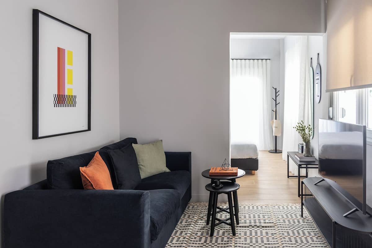 Ein modernes Wohnzimmer mit einem schwarzen Sofa, einem kleinen runden Tisch und einem großen Flachbildfernseher.