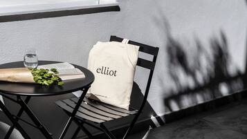 A table with a chair, a glass of water, a bag, and some greens on the table.