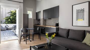A modern living room with a grey sofa, a coffee table with a book and a vase of flowers, and a dining area with chairs and a table.