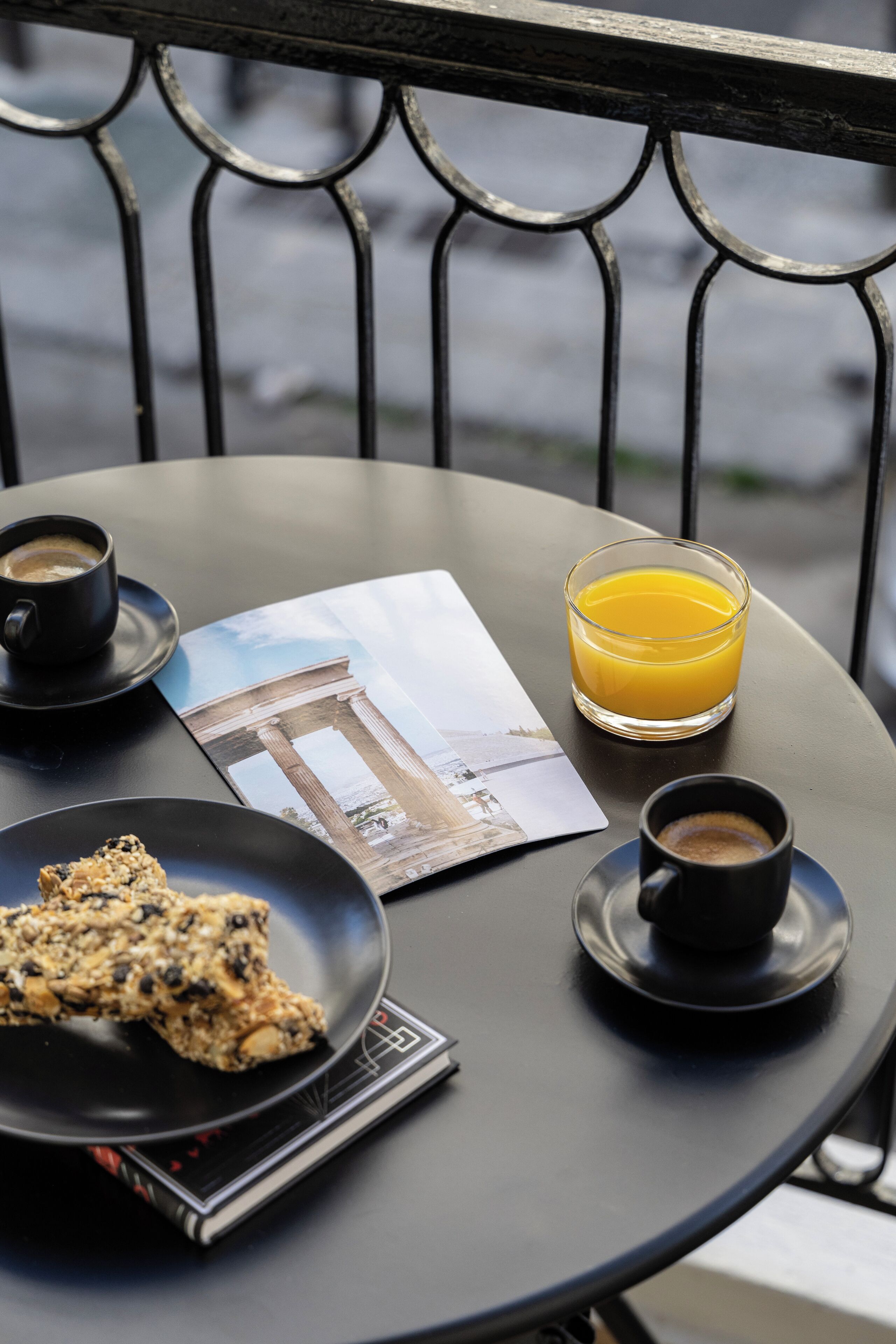 A table with a cup of coffee, a glass of orange juice, and a plate of food on a balcony.