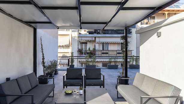 An outdoor seating area with two sofas and a table, surrounded by potted plants. - Elliot Petralona, Athens (Athens)