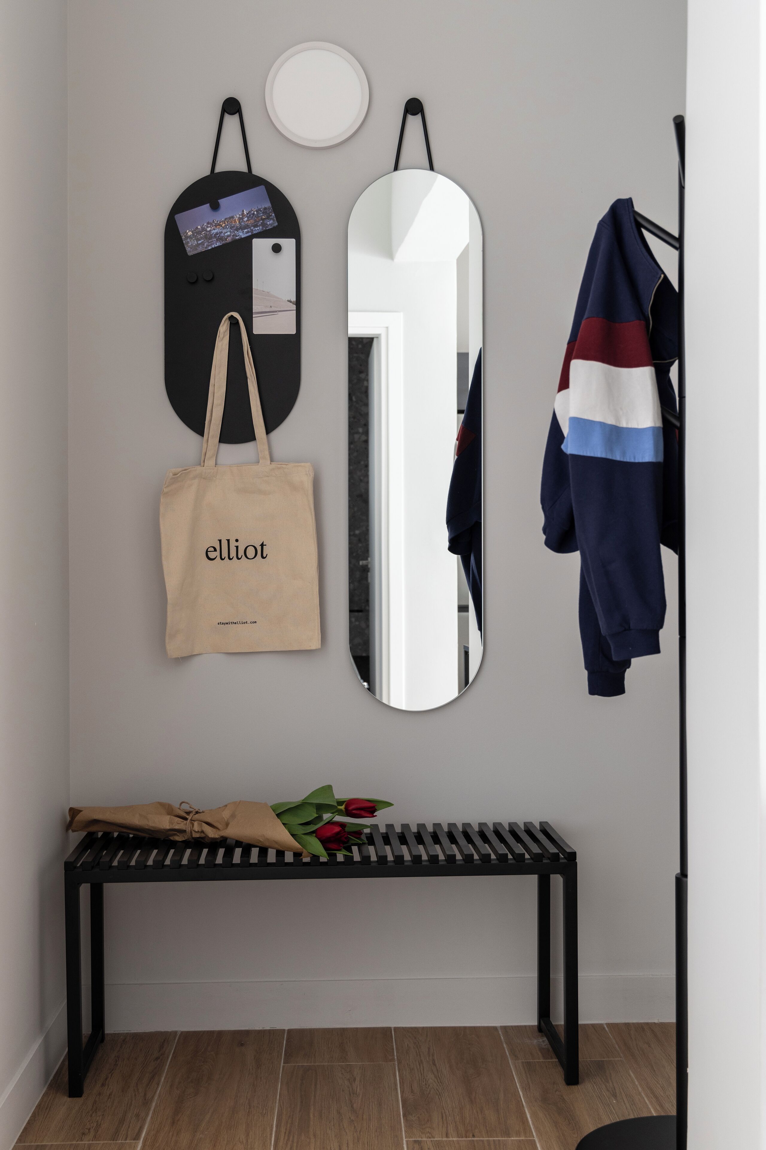 Een modern interieur met een bankje, een spiegel, een kapstok en een tas aan de muur.