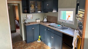 A kitchen with dark blue cabinets, a window with a view, a sink, and a stove. - 6 Berth Caravan Next To The Beach-ingoldmells-dog Friendly (Skegness)