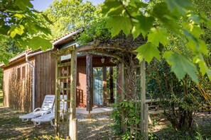 A wooden cabin with a covered porch, a ladder, and a bench. - Verdier, Gîte with shared swimming pool in Dordogne (Saint-Avit-Sénieur)