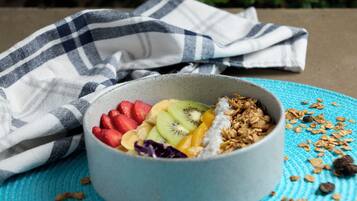 Een schaal met fruit en granola op een blauwe placemat.
