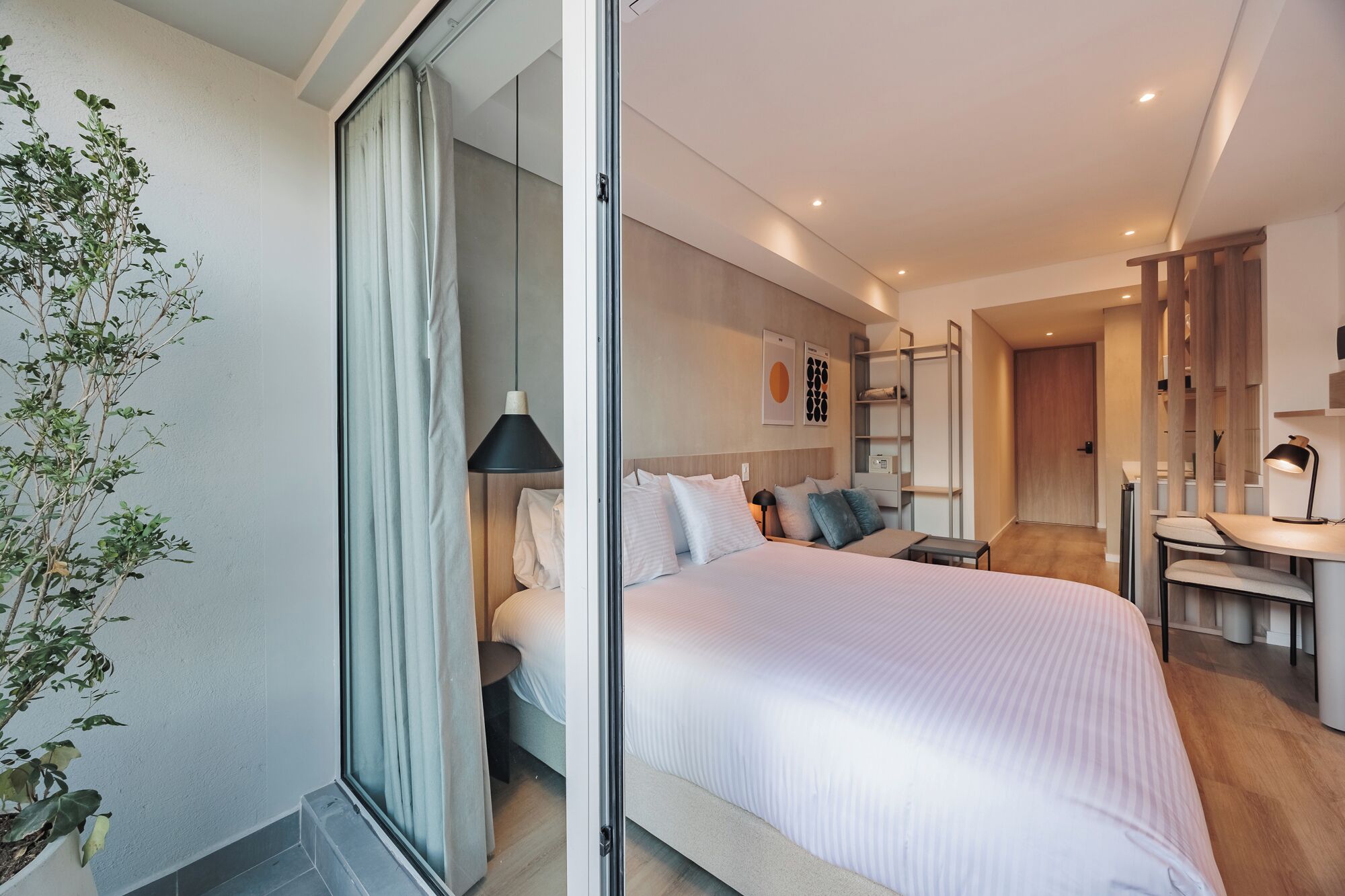 Ein modernes Schlafzimmer mit einem großen Bett, Nachttischen, einem Schreibtisch und einem Sessel.