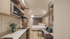 Een compacte hotelkamer met kitchenette, een bed en een zithoek.