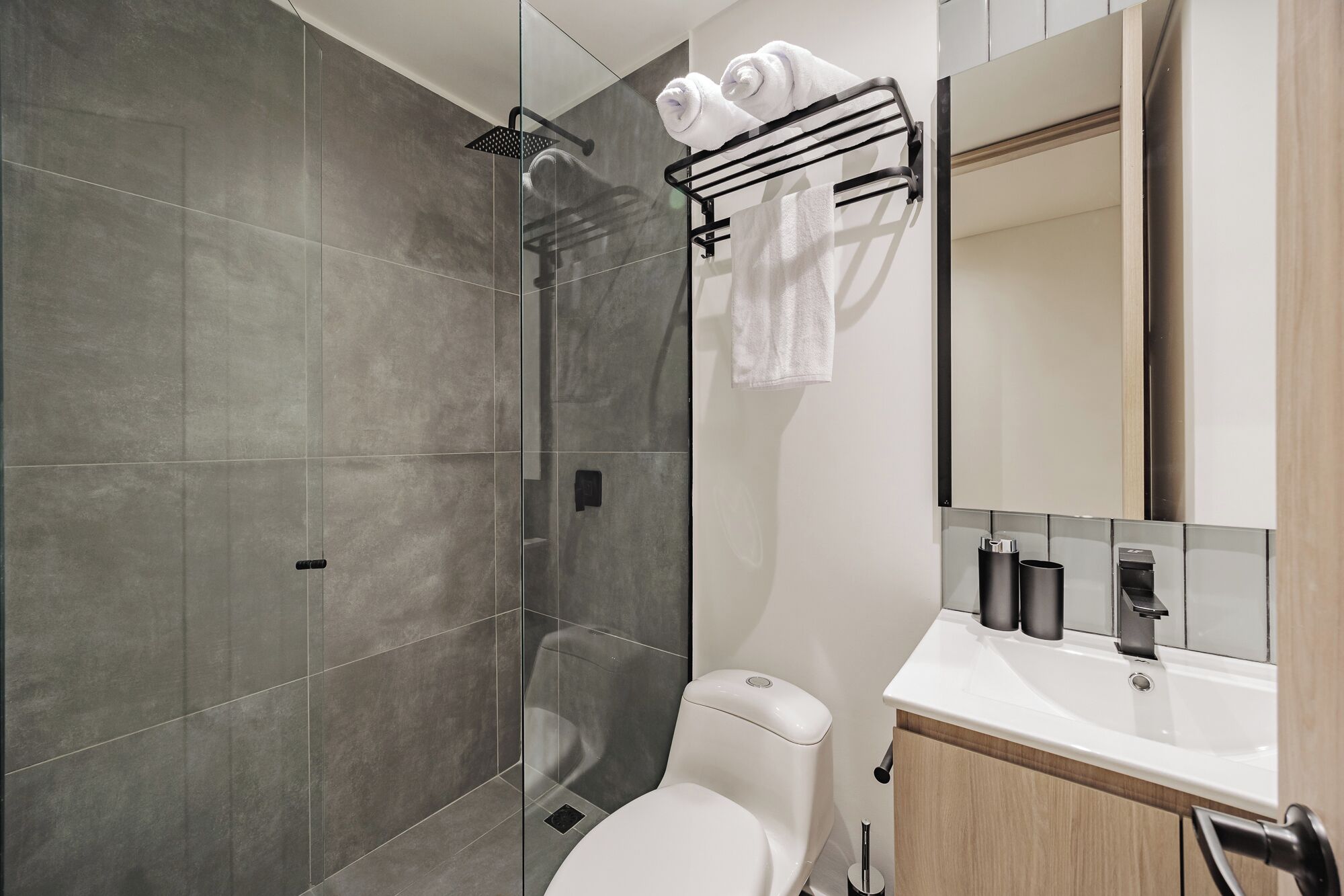 A modern bathroom with a shower, toilet, and sink.