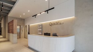 Een receptiebalie met een modern design, een naambordje met de tekst 'Quadrão' en een houten paneel aan de linkerkant.