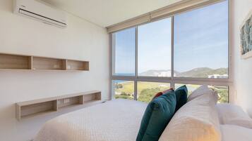 A bedroom with a large window, a bed with pillows, and built-in wooden shelves.