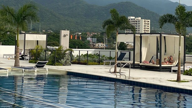 A swimming pool with lounge chairs and a view of mountains. - U-GO Porto Horizonte Junto al Mar Sta Mta (Santa Marta)