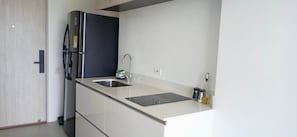 A compact kitchen with a built-in refrigerator, a sink, and a countertop with a cutting board. - U-GO Porto Horizonte Junto al Mar Sta Mta (Santa Marta)